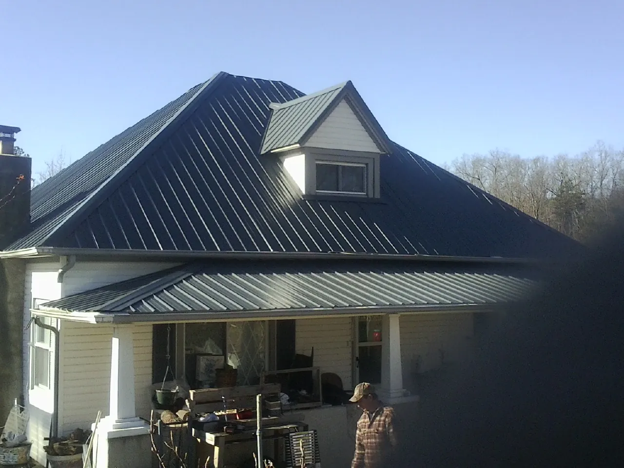 Dark blue standing seam metal roof with a dormer above a front porch in Conyngham