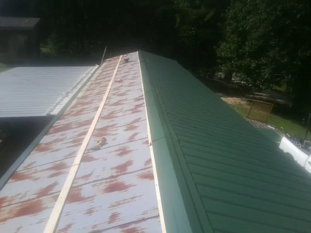 Old rusted panels beside newly installed green metal roofing — Wind Damage Roof Repair by Roofing Brothers in Conyngham