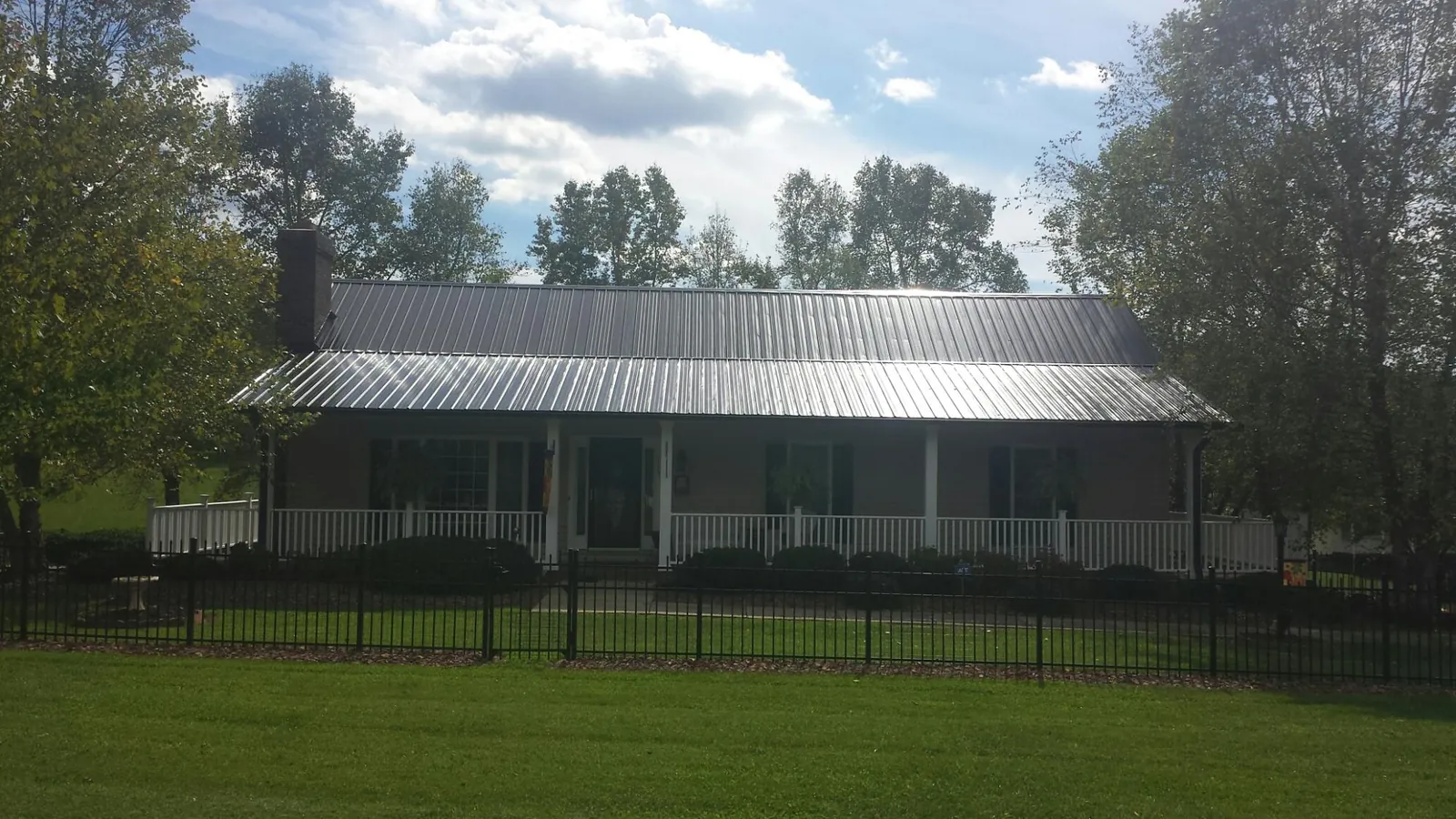 Gray metal roof on a brick ranch with a full width front porch — Gutter Guard Installation work by our crew in Conyngham