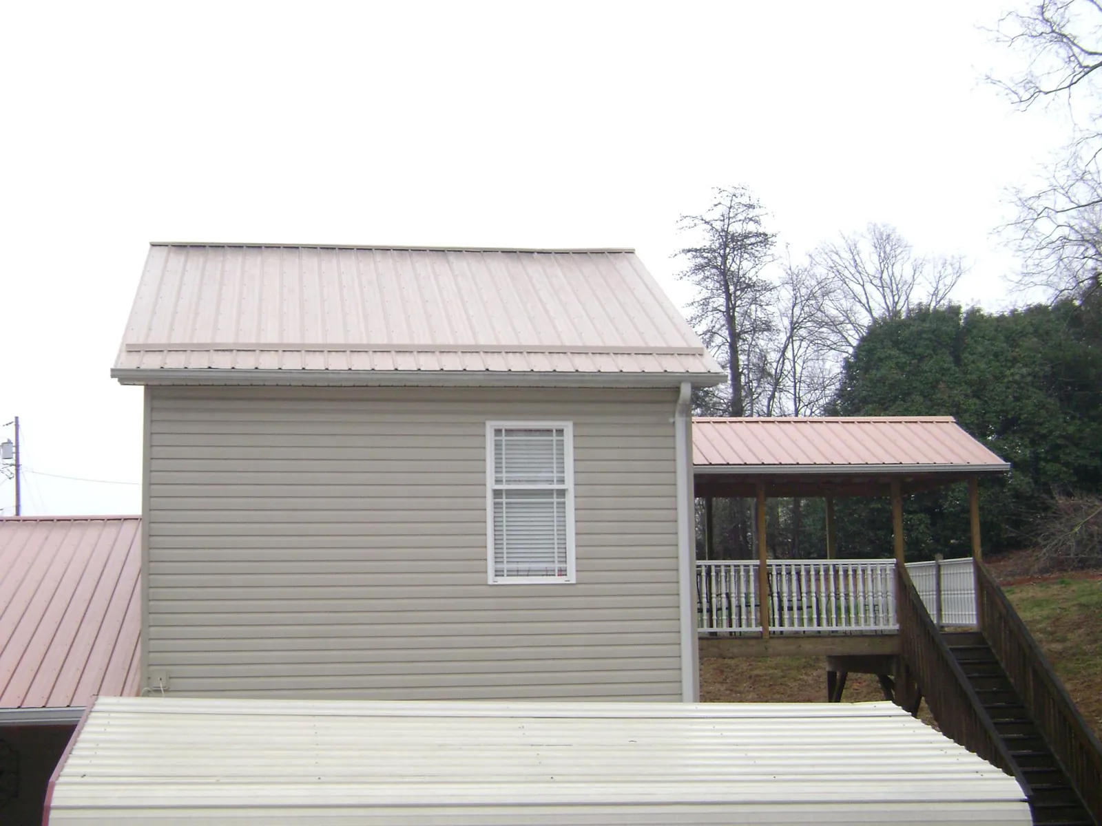 Tan metal roofs on a two story addition and attached porch, from a Roof Replacement job in Conyngham
