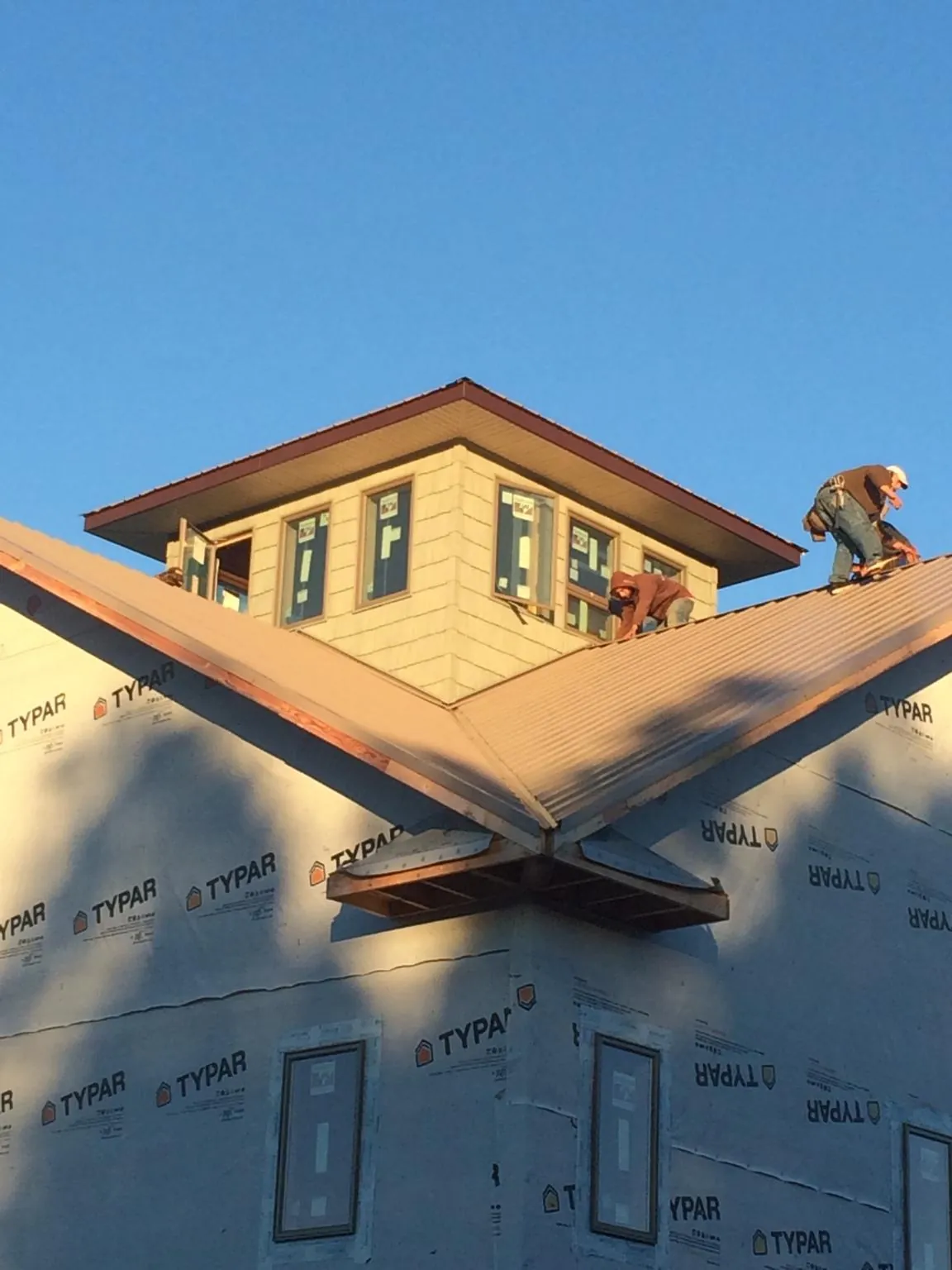 Roofers working around a rooftop cupola on a new metal roof at sunset — Roof Waterproofing in Conyngham by Roofing Brothers